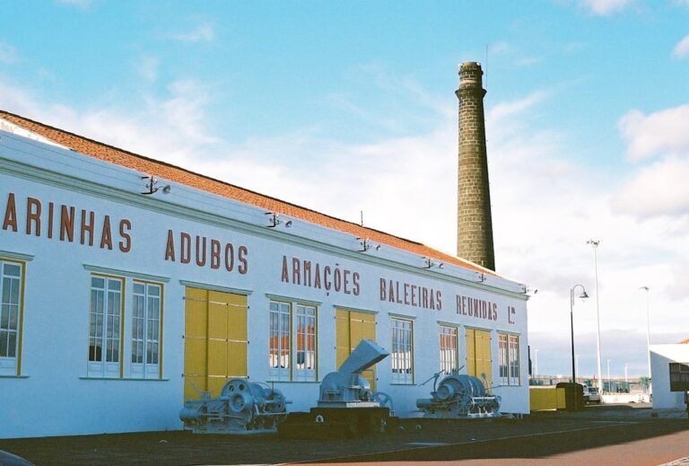 grandes navegacoes - a white building with yellow shutters and windows