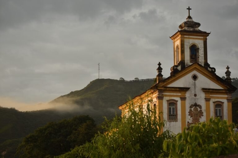 igreja primitiva - a building with a tower and a hill in the background